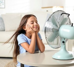 reduce electricity costs - Child sitting infront of a fan with wind blowing her hair
