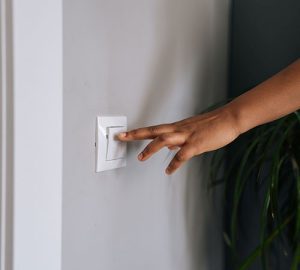 reduce electricity costs - Person with hand on lightswitch