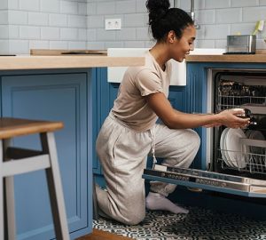 reduce electricity costs - Woman packing dishwasher