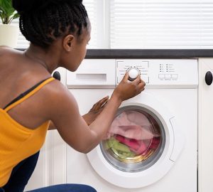 reduce electricity costs - Woman setting washmachine setting in kitchen